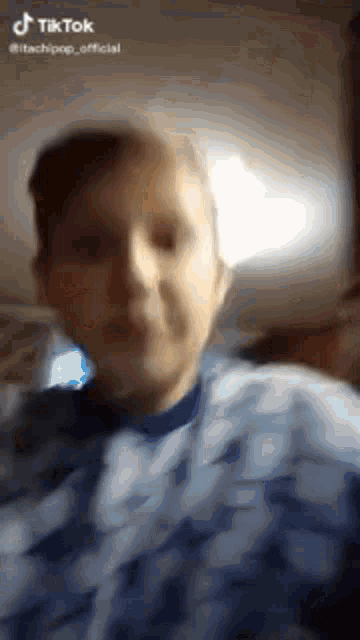 a man in a blue shirt is taking a selfie with a camera .
