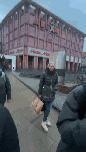 a woman walking in front of a building that has alexa on it