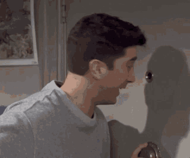 a man in a grey shirt looks through a peephole in a door