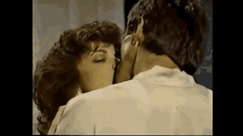 a man and a woman are kissing in front of a mirror .