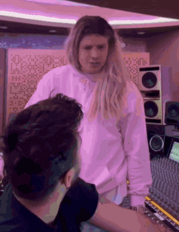 a woman in a pink sweatshirt talks to a man in a black shirt