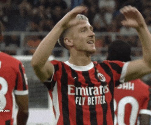 a man in an emirates fly better jersey celebrates