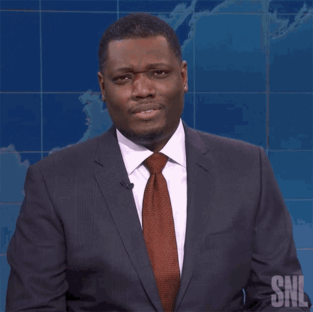 a man in a suit and tie is standing in front of a snl logo