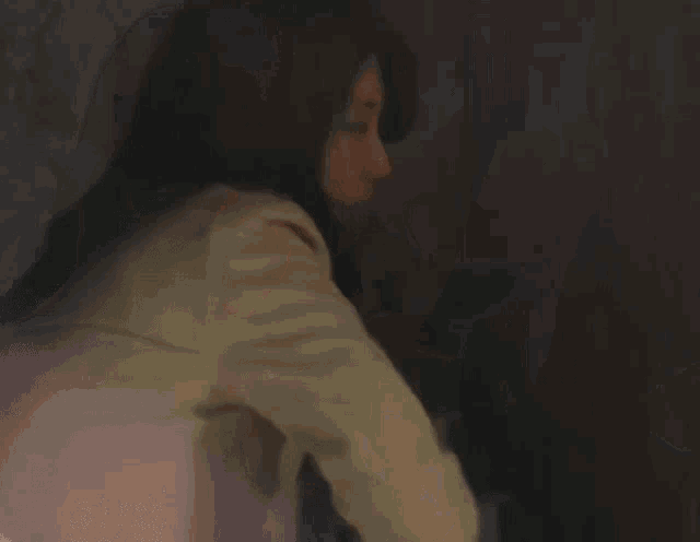 a woman in a trench coat is holding a gun and pointing it at the camera .