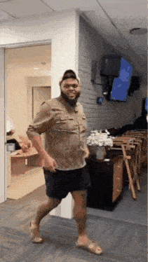 a man with a beard is standing in a hallway wearing shorts and sandals