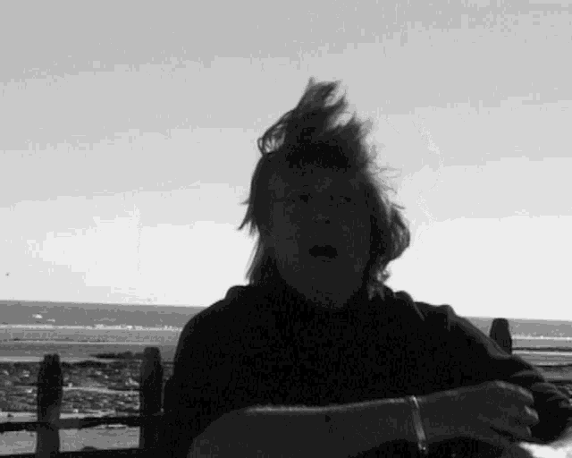 a man with his hair blowing in the wind looks at the camera