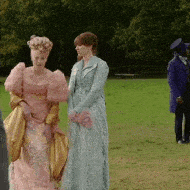 a woman in a pink dress is standing next to another woman in a blue dress in a field .
