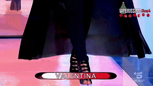 a woman is walking down a runway with the name valentina on the bottom of the screen