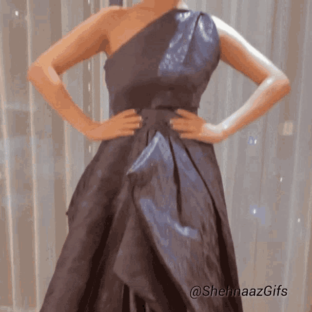 a woman in a black dress is standing with her hands on her hips and the words @shehnaazgifs on the bottom