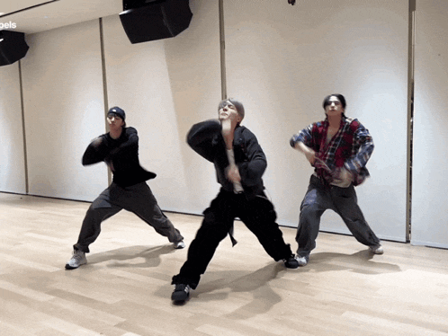 three people are dancing in a room with the word angels on the bottom left