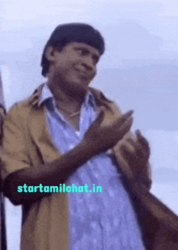 a man applauds in front of a sign that says starttamilchat.in on it