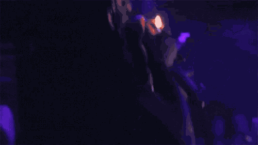 a person is smoking a cigarette in a dark room with purple lights .