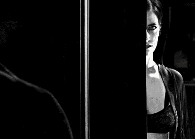 a black and white photo of a woman wearing a black bra