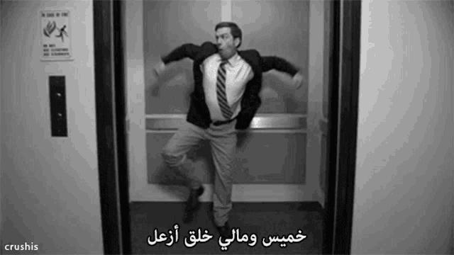 a man in a suit and tie is dancing in an elevator with arabic writing on it .