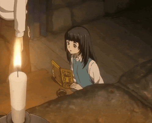 a girl reading a book next to a candle