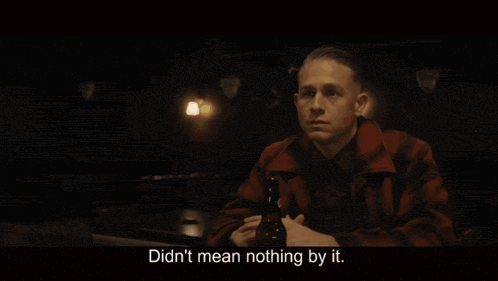 a man sitting at a table with a bottle of beer and the words didn 't mean nothing by it