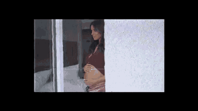 a pregnant woman is standing in front of a window .