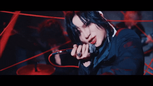 a woman is singing into a microphone in a dark room surrounded by red wires .