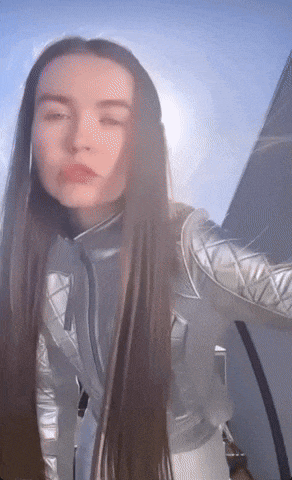 a woman with long hair wearing a silver jacket