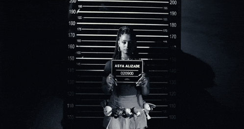 a woman holding a sign that says asta alizade 020800