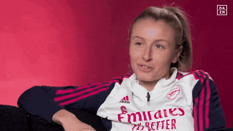 a woman is wearing a emirates better jersey while sitting on a couch .