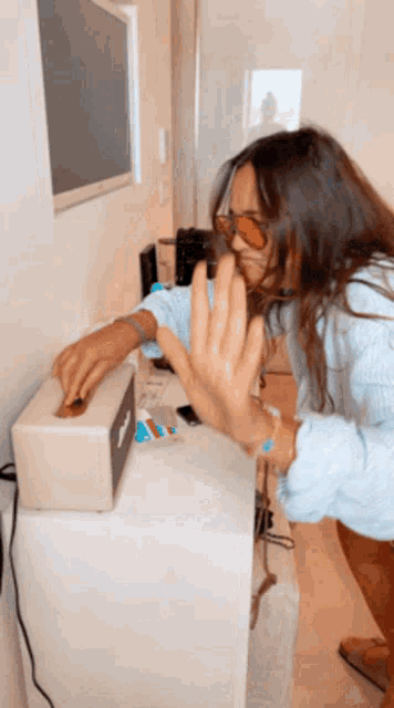 a woman wearing sunglasses and a blue shirt is putting something in a box with the letter t on it