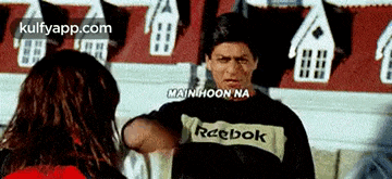 a man wearing a reebok sweatshirt is talking to a woman .