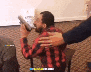 a man in a red plaid shirt is holding a gun