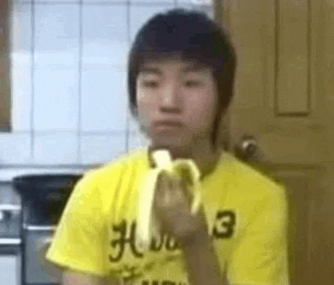 a young man is eating a banana in a kitchen .