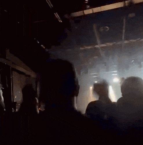 a crowd of people are dancing in a dark room with their arms in the air