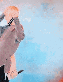 a man in a grey sweater is holding a microphone and singing into it .