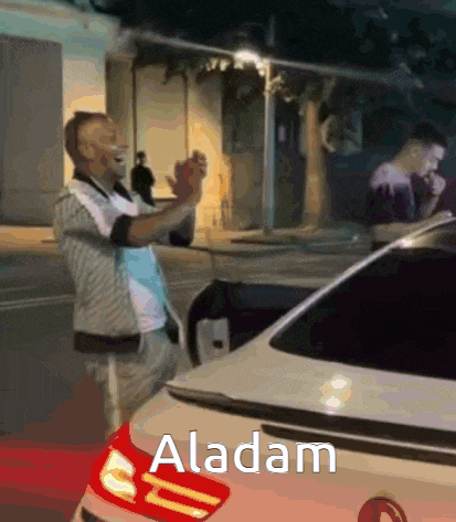 a man is standing in front of a white car with the word aladam on the back