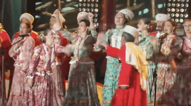 a group of people are singing into microphones and dancing on a stage