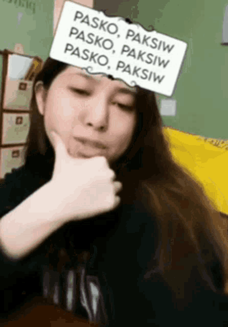 a woman is wearing a sign on her head that says pasko