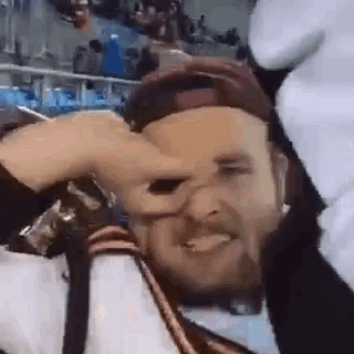 a man with a beard is making a funny face while wearing a hat and gloves .