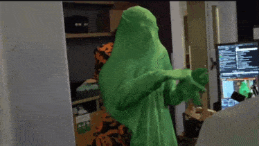 a person in a green suit is standing in front of a computer screen