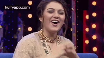 a woman is sitting on a blue couch laughing with her eyes closed .