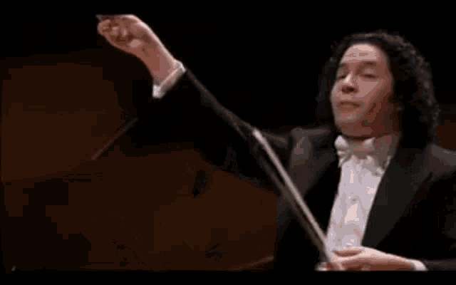 a man in a tuxedo is holding a conductor 's baton