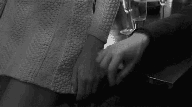 a black and white photo of a couple holding hands .