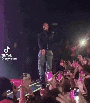 a man is standing on a stage in front of a crowd with a tiktok watermark