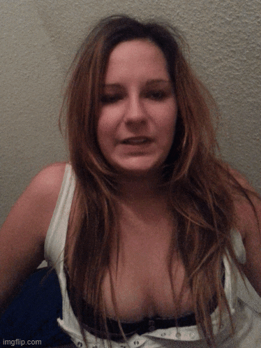 a woman 's breast is visible in a white tank top with a black bra
