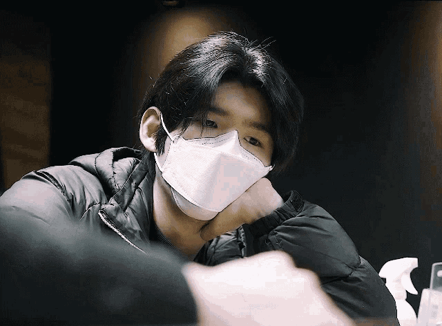 a man wearing a white face mask with a black jacket