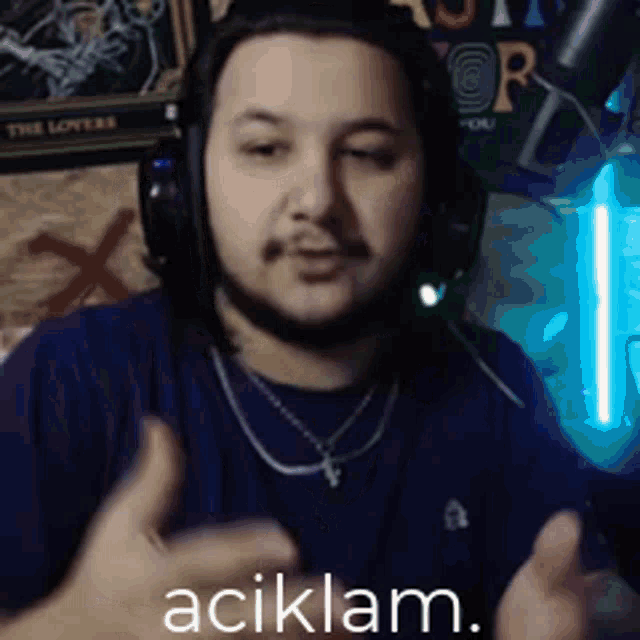 a man wearing headphones and a necklace is making a funny face and says açiklam .