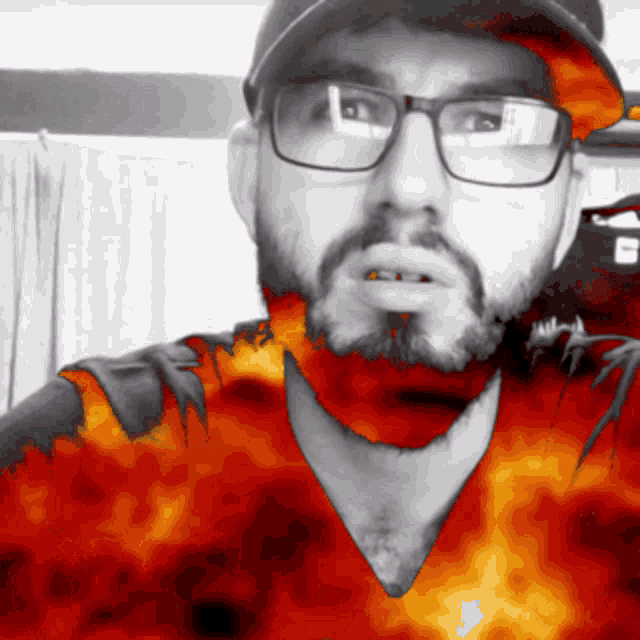a man with glasses and a beard is wearing a hat with flames on it