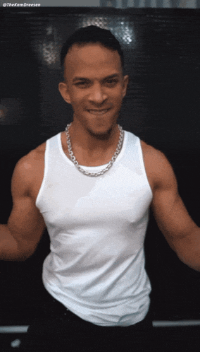 a man wearing a white tank top and a silver chain necklace