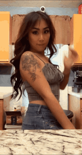 a woman with a tattoo on her arm is standing in front of a counter