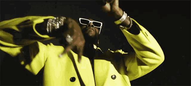 a man wearing a yellow jacket and sunglasses is dancing