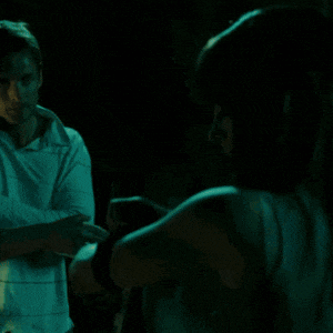 a woman in a blue tank top is standing in front of a man in a white shirt