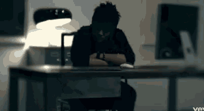 a man is sitting at a desk with his head resting on his hands