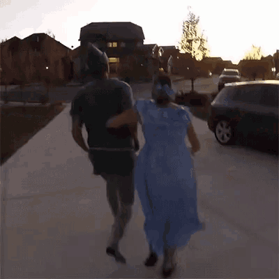 a man dressed as peter pan and a woman dressed as cinderella walk down a street